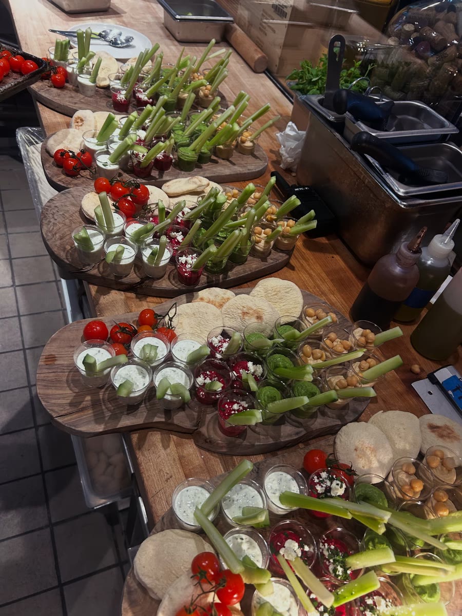 Catering boards of pita, roasted tomatoes and colorful dips in shot glasses, ready to serve