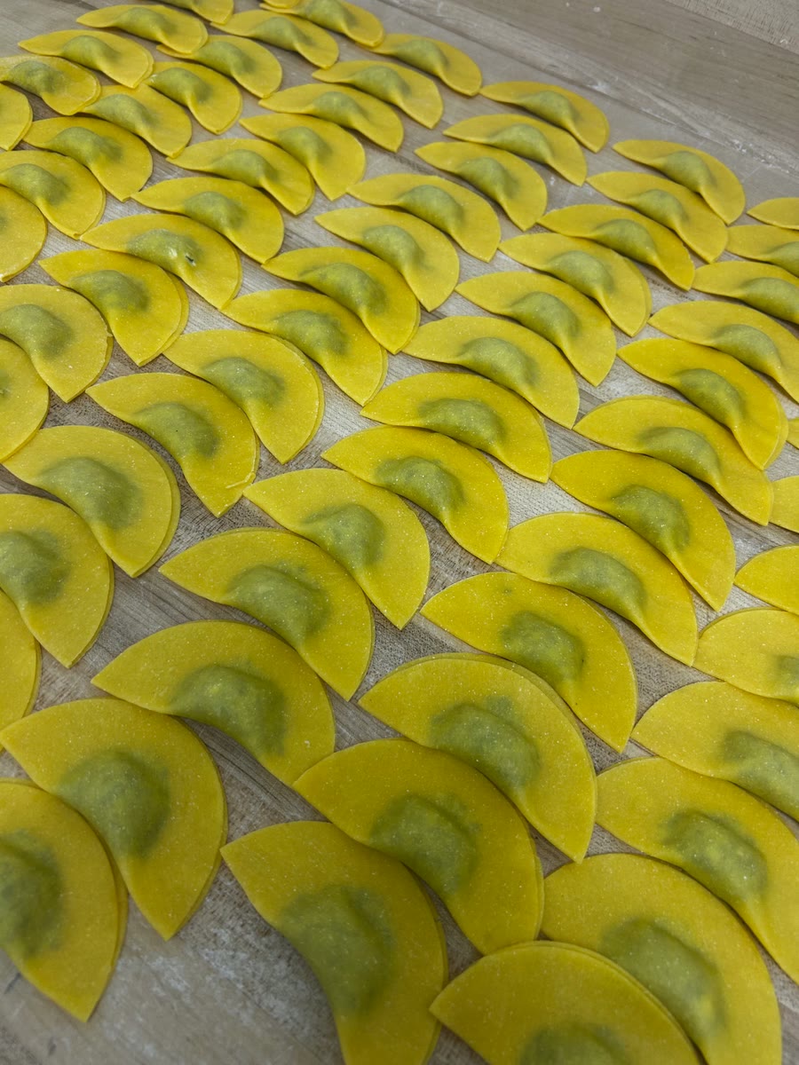 Handmade stuffed pasta laid in rows on a floured wooden board